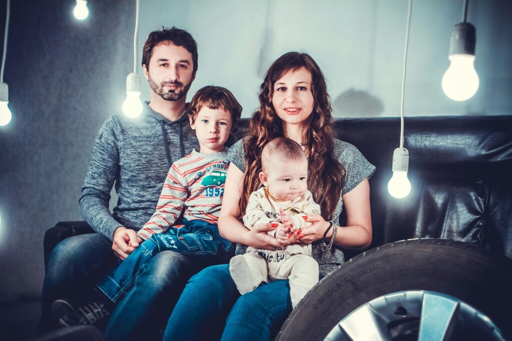 Warm family photo indoors with creative lighting setup, capturing togetherness and joy.