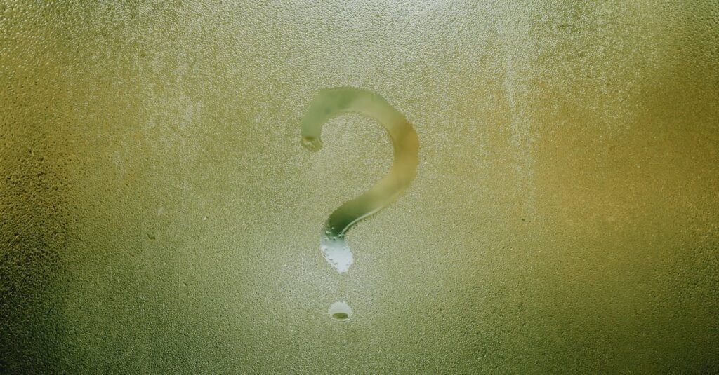 A question mark drawn on foggy glass, evoking curiosity and mystery.