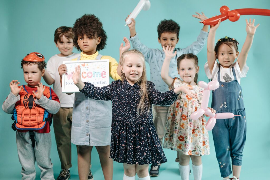 Group of diverse children having fun with balloons and costumes in kindergarten.